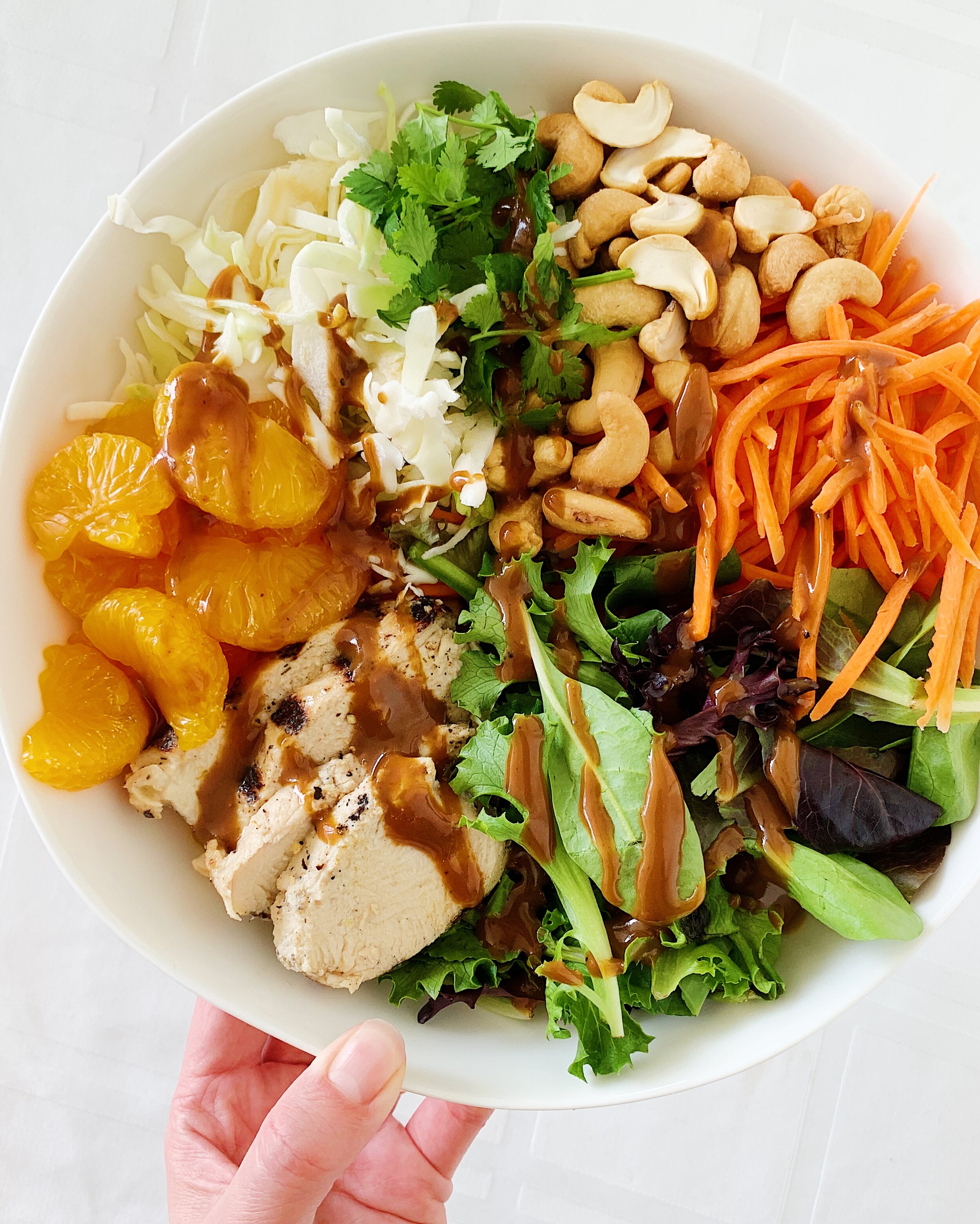Asian chicken salad with mandarine oranges, shredded carrots, cashews, cabbage, cilantro, and peanut sauce 